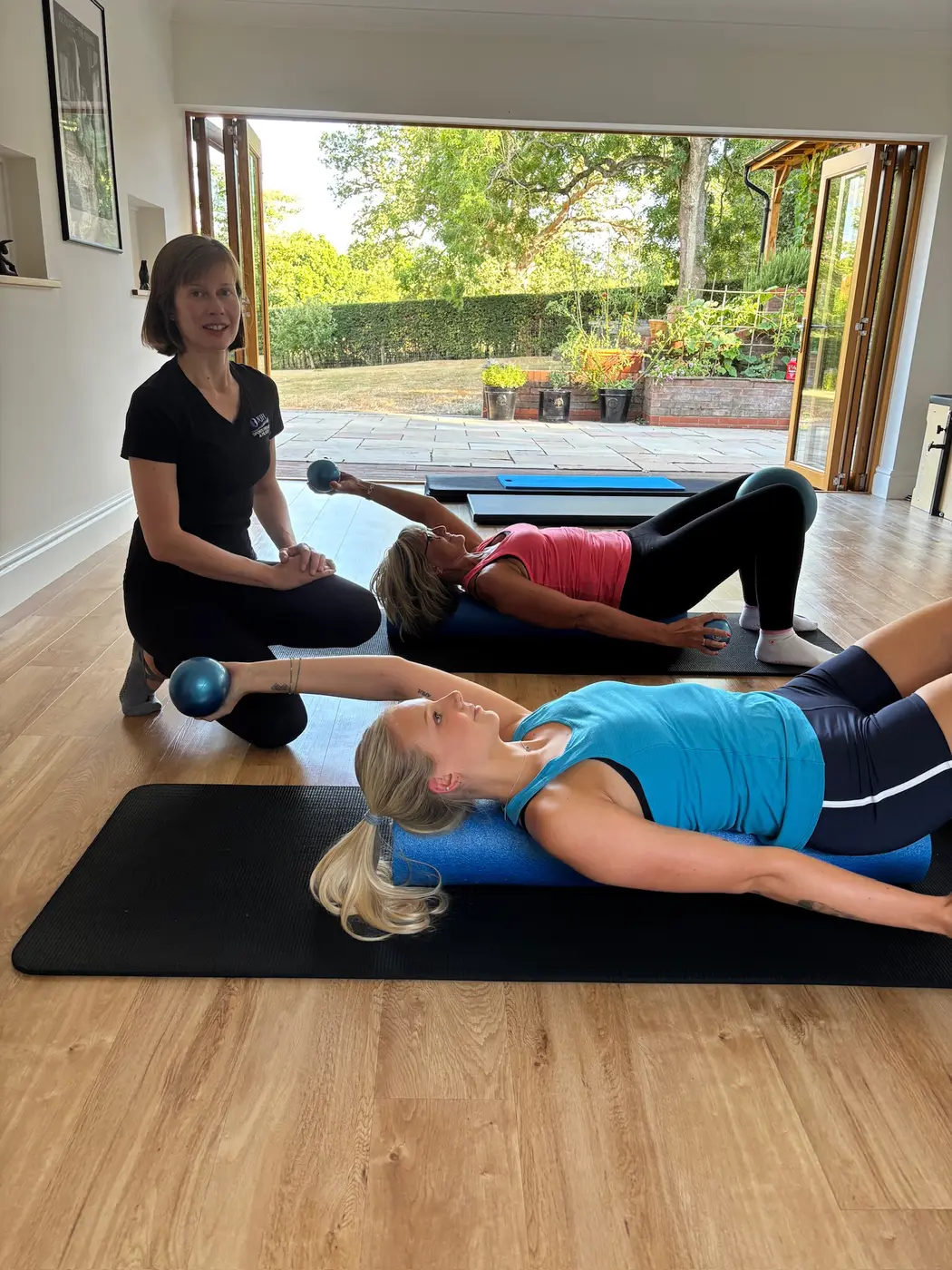 Natasha guiding a small group Pilates class in the Studham studio, mats laid out and the garden doors open